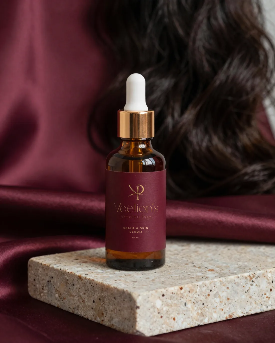 Amber Veelion's scalp and skin serum bottle with a burgundy and gold label